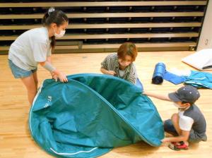 避難所用テントの組み立てをする親子