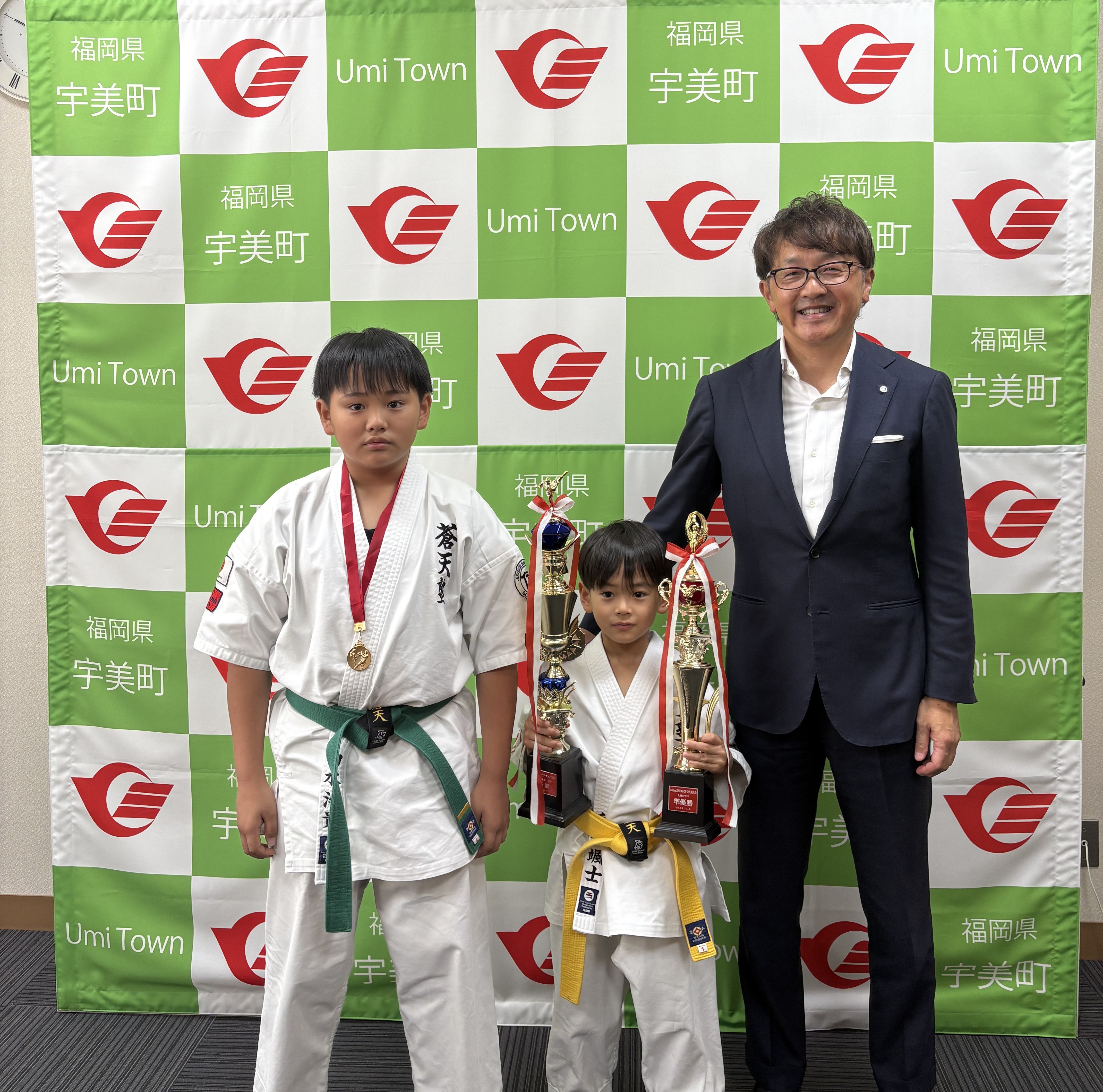トロフィーを持つ颯士さんとメダルを持つ治貴さんと町長