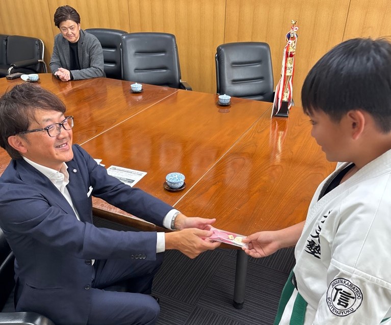 願掛けにメダルを渡す町長