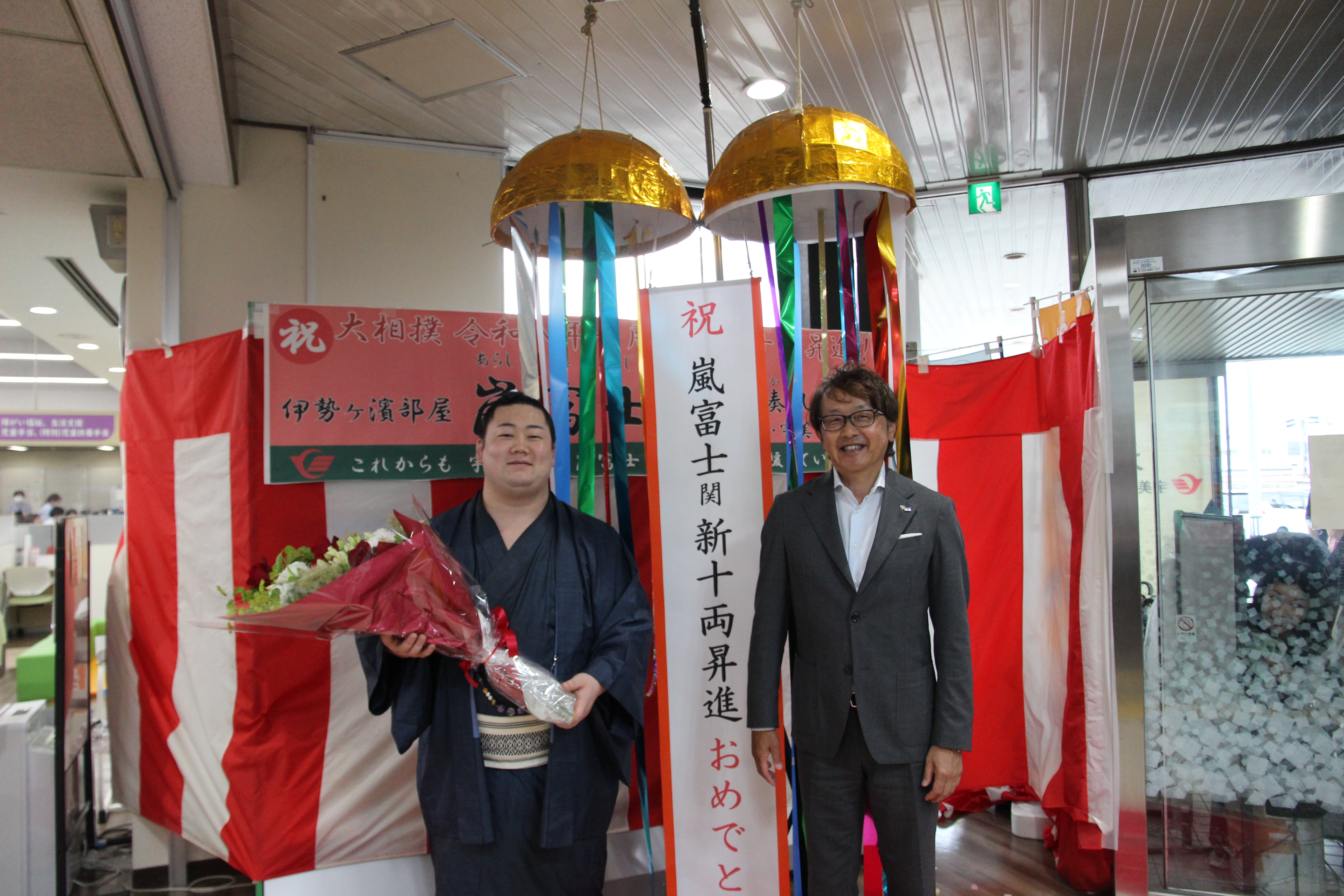 くす玉の前で花束を持つ嵐富士関と安川町長