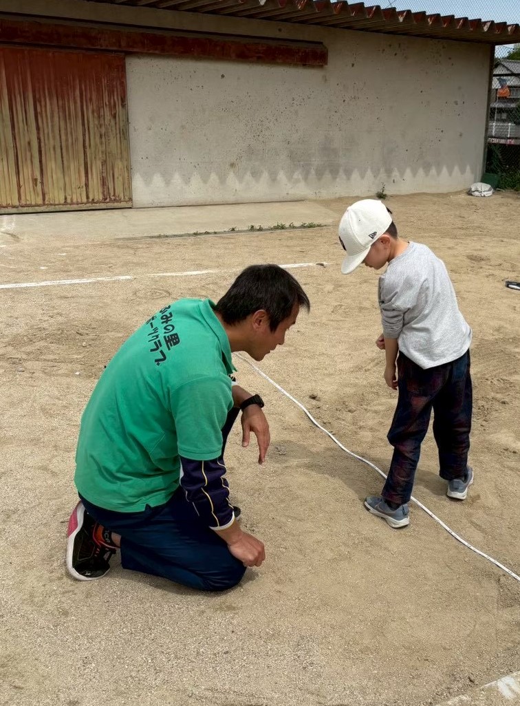 宇美小学校で立ち幅跳びの測定をする郡島委員